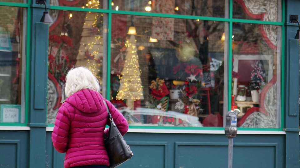 Une dame devant une vitrine décorée pour les Fêtes.
