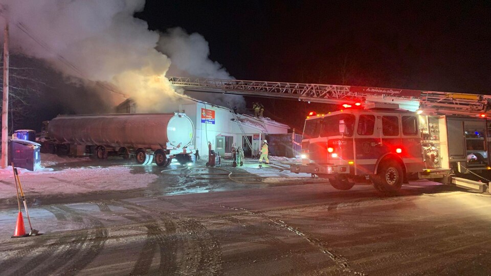 Un camion de pompiers devant un édifice en feu.