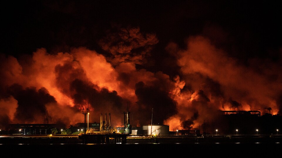 Des flammes et de la fumée s'élèvent du site d’un dépôt de carburant ravagé par un gigantesque incendie.