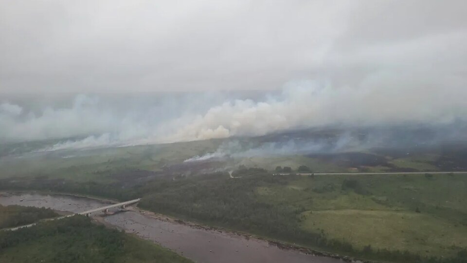 Photographie aérienne d'un grand feu de forêt près d'une route.