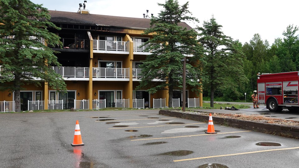 Bâtiment endommagé par le feu avec un camion de pompiers.