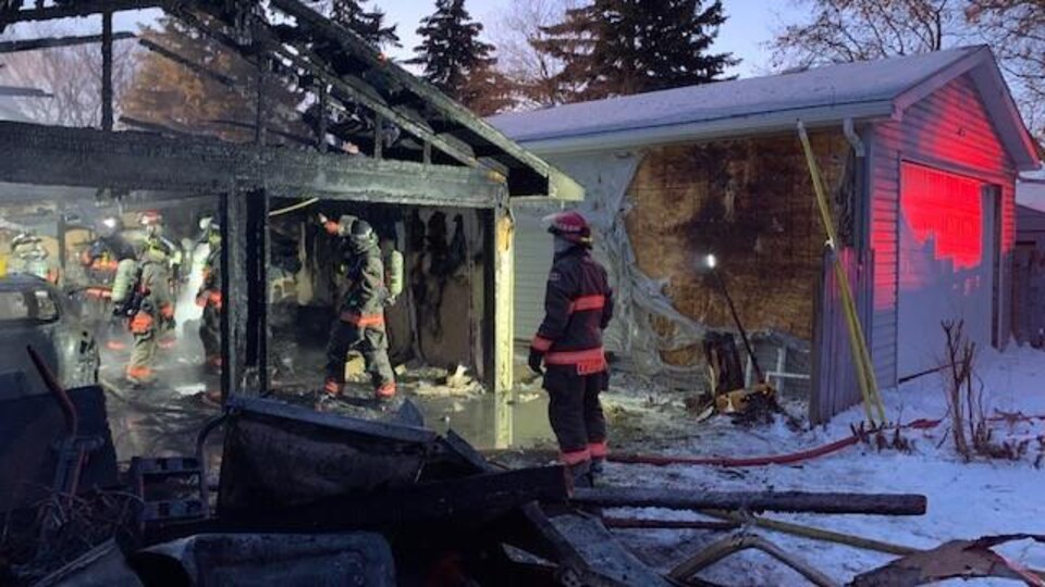 Des pompiers examinent l'intérieur du garage une fois l'incendie maîtrisé. 