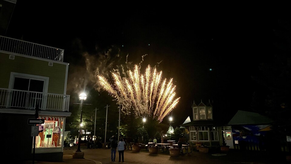 Des gens regardent des feux d'artifice la nuit au centre ville.