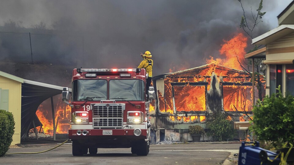 Un pompier attend d’être alimenté en eau alors qu’il combat un incendie dans un parc de maisons mobiles d’Alpine Oaks, en Californie, le 6 juillet 2018.
