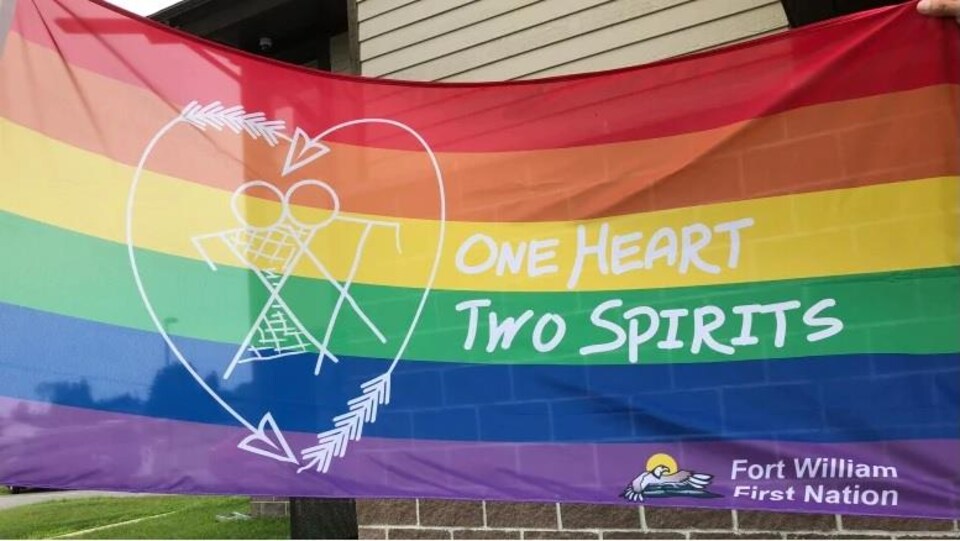 Un drapeau multicolore un homme et une femme dans un cœur avec deux flèches
