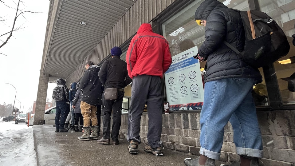 Des gens attendent dehors devant un immeuble.