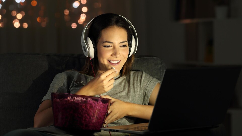 Une femme regardant un film sur son ordinateur.