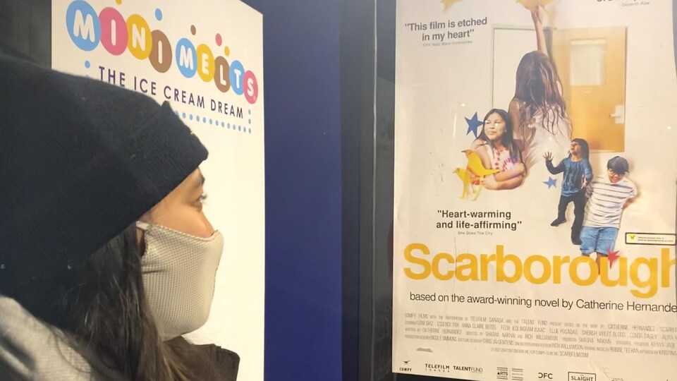 Une femme regarde l'affiche du film « Scarborough » avant d'entrer dans la salle de cinéma.
