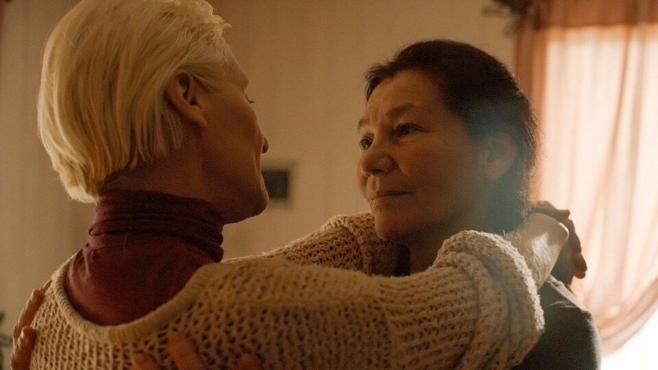 Deux femmes s'enlacent et se regardent tendrement.