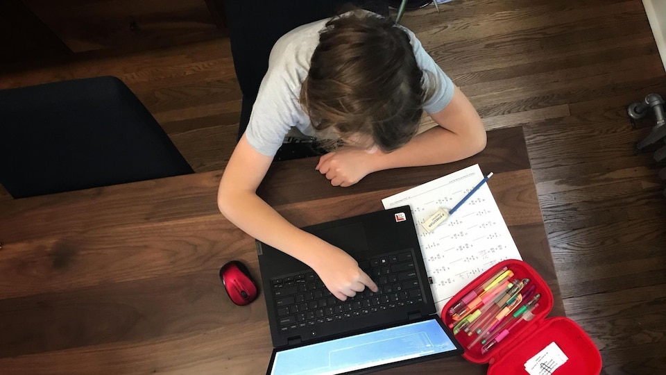Un jeune étudie sur une ordinateur.