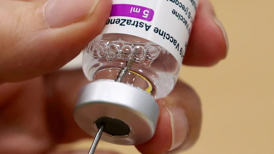 La main d'une personne qui remplit une seringue avec une fiole du vaccin AstraZeneca contre la COVID-19.