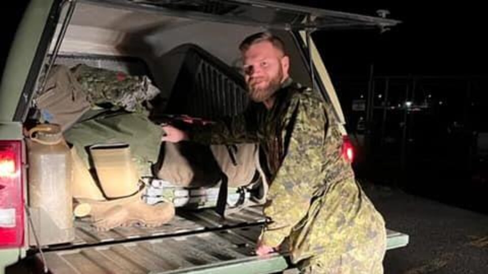 Un militaire remplit le derrière de son véhicule de matériel militaire. 