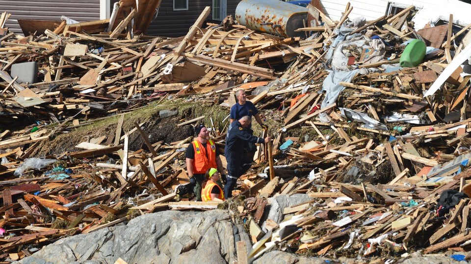 Des secouristes fouillent les débris d'une maison.