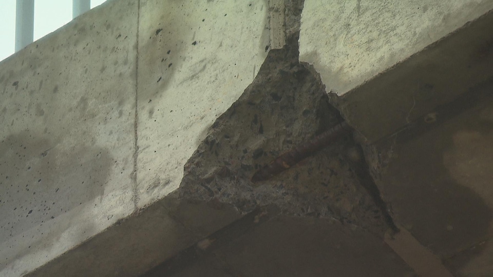 Un trou dans le béton permet de voir un câble de métal rouillé.