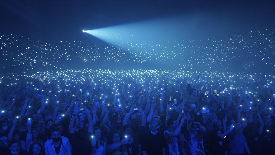 Une salle comble avec des spectateurs qui agitent leur téléphone