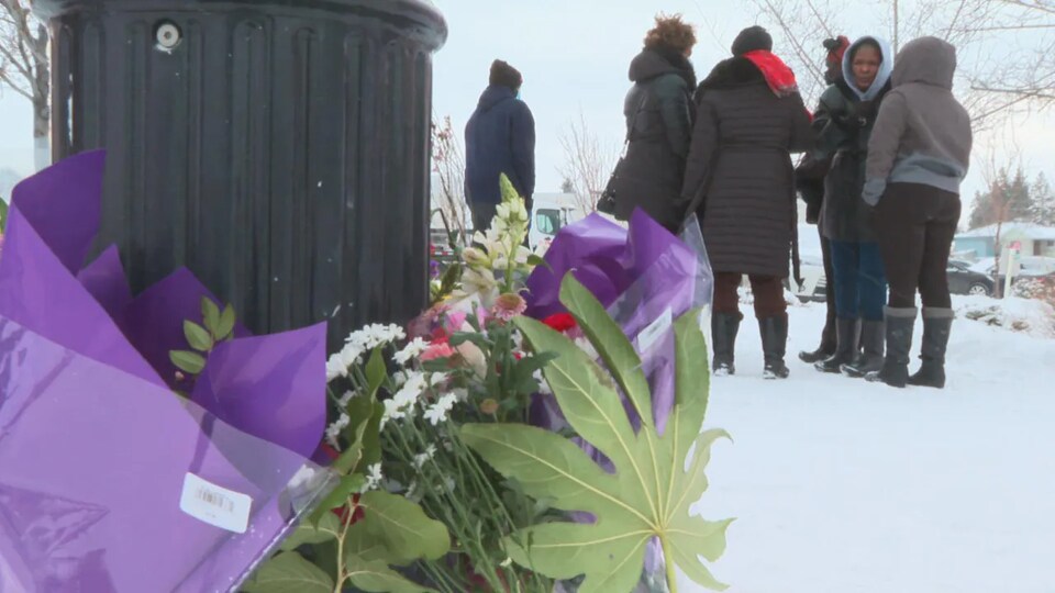 Des fleurs sont placées à l'endroit où la police a tiré sur un homme noir à Calgary pendat que des passants se font la conversation.