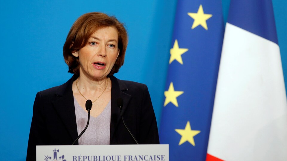 La ministre française des Armées, Florence Parly, en train de faire une déclaration derrière un lutrin sur lequel est écrit « République française ». Un drapeau de la France et de l'Union européenne sont accrochés derrière elle.