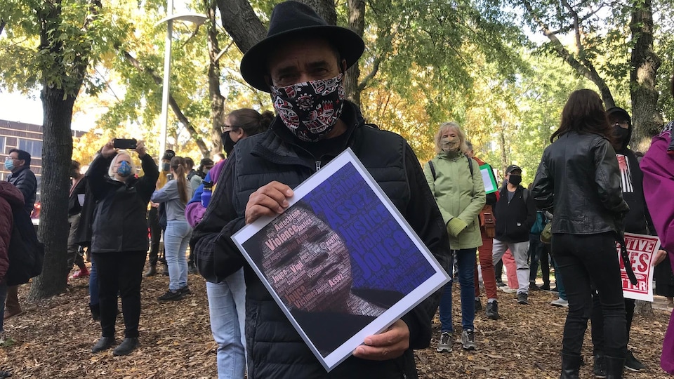 Florent Vollant porte un masque et tient une affiche.