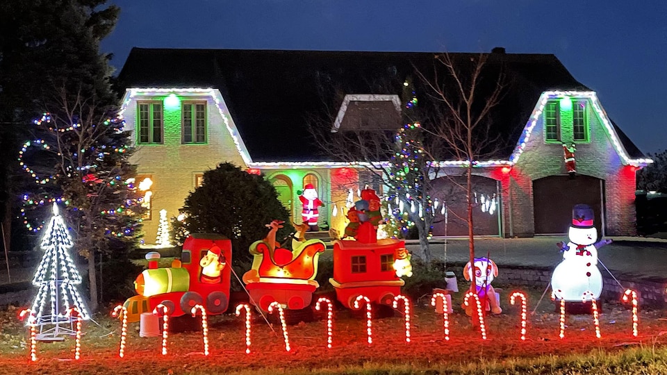 Une maison illuminée avec des cannes de Noël lumineuses et un bonhomme de neige gonflable.