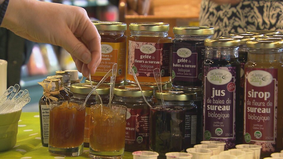 Du jus de sureau et de la gelée sont sur une table. Une personne goûte à la gelée.