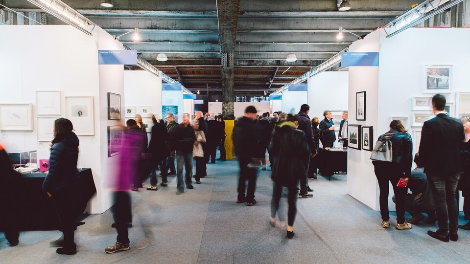 Des gens se promènent dans une exposition d'œuvres d'art. 