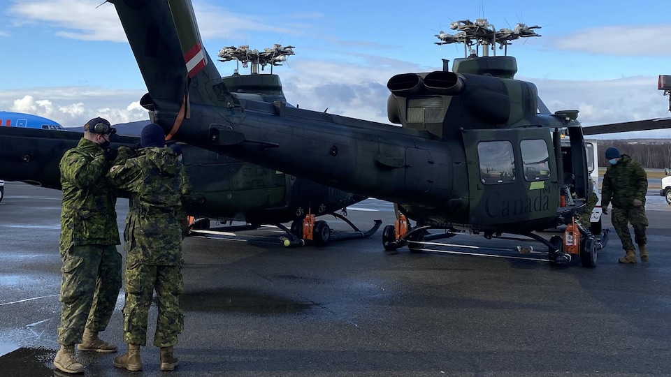 Un gros hélicoptère militaire avec l'inscription Canada sur un tarmac, avec des militaires en uniforme autour.