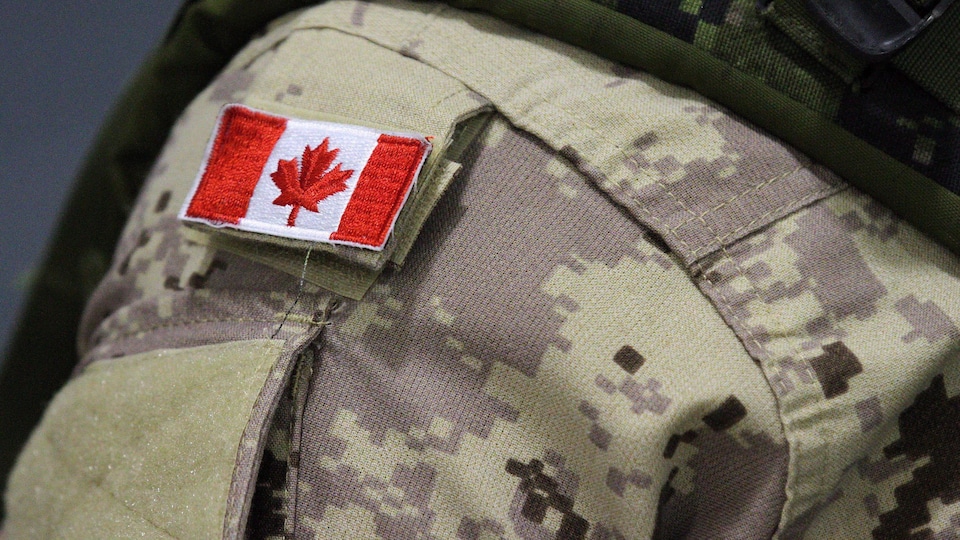 Zoom sur le drapeau du Canada qui figure sur l'uniforme porté par un militaire.