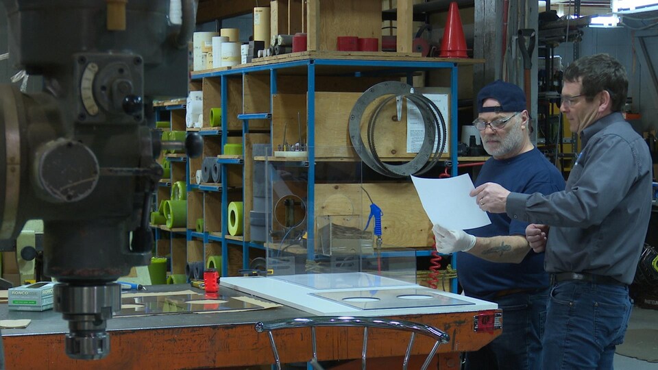 Deux hommes devant un banc de travail.
