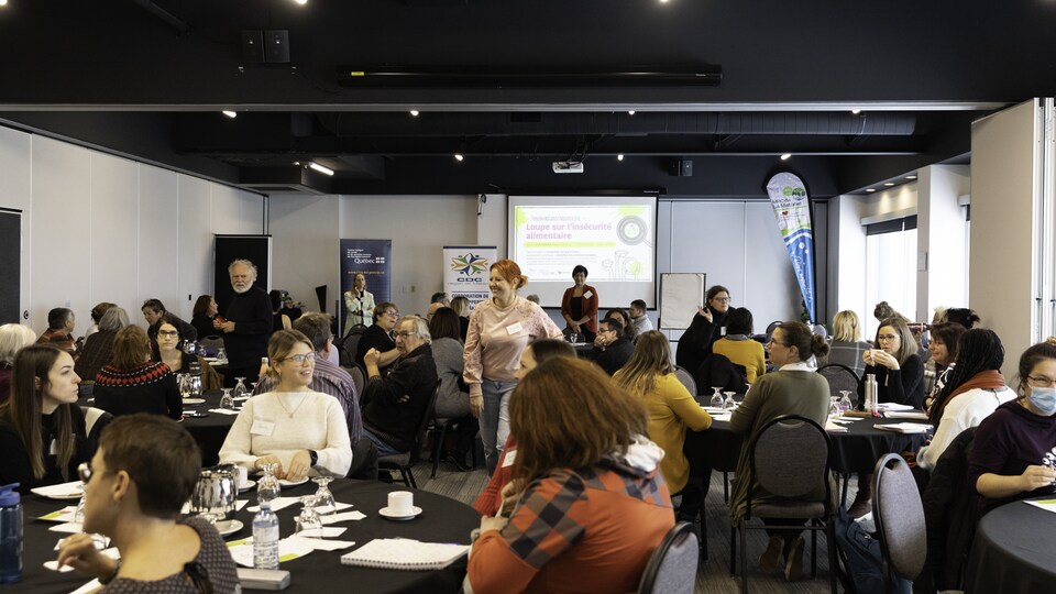 Des gens assis à des tables dans une salle de conférence.