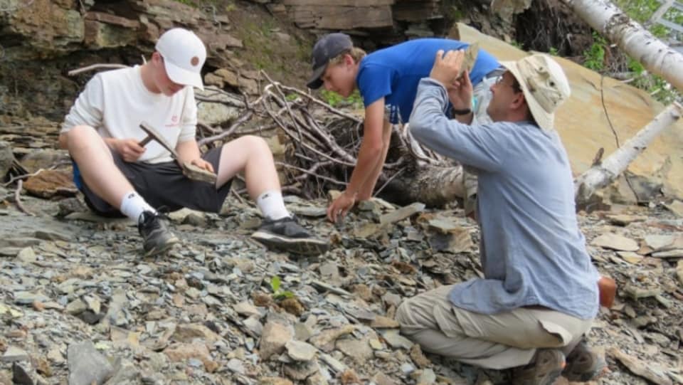 Trois hommes explorent un site rocheux. 