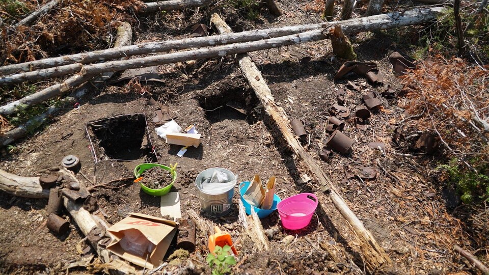 Des trous sont creusés dans la terre et des objets sont répartis dans de petits récipients.