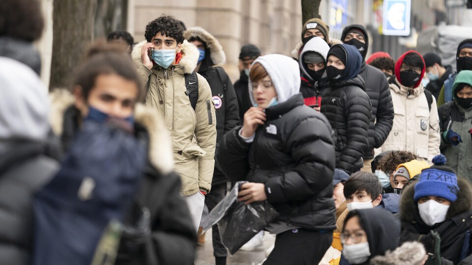 De nombreuses personnes entassées dans une file attendent l'ouverture des boutiques.