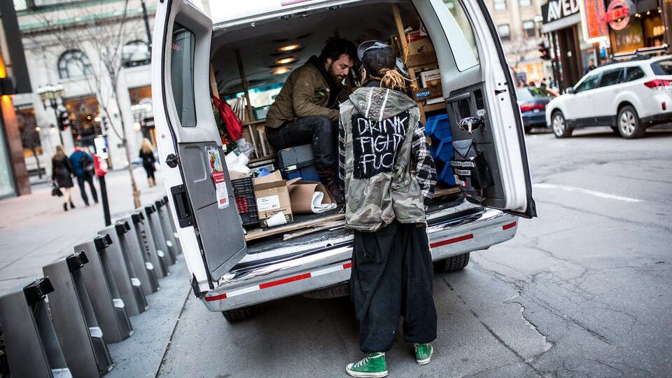 Deux personnes à l'arrière d'une camionnette pleine de livres.