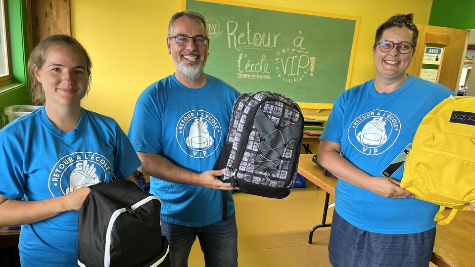 Les membres de l'organisme tenant chacun un sac d'école rempli de fournitures scolaires.