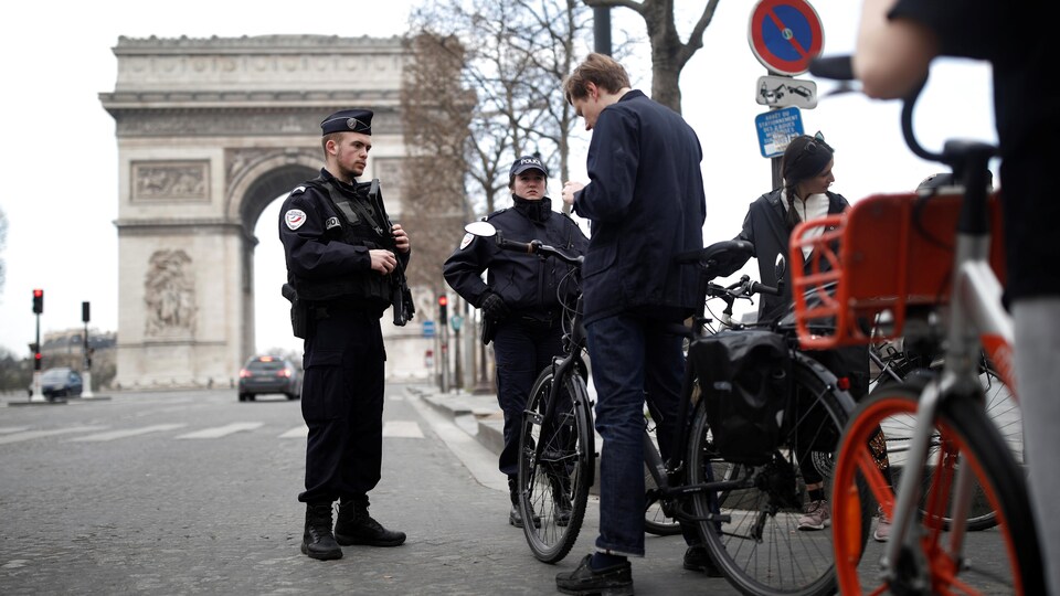 Des policiers français contrôlent les cyclistes devant l'Arc de triomphe à Paris.