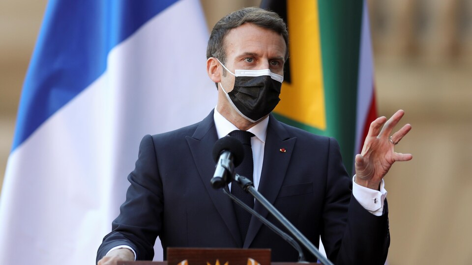  Le président Macron derrière un lutrin et masqué.