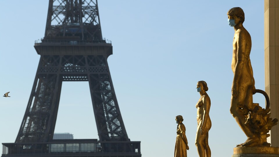 Des statues à la place du Trocadéro à Paris portent des masques médicaux.