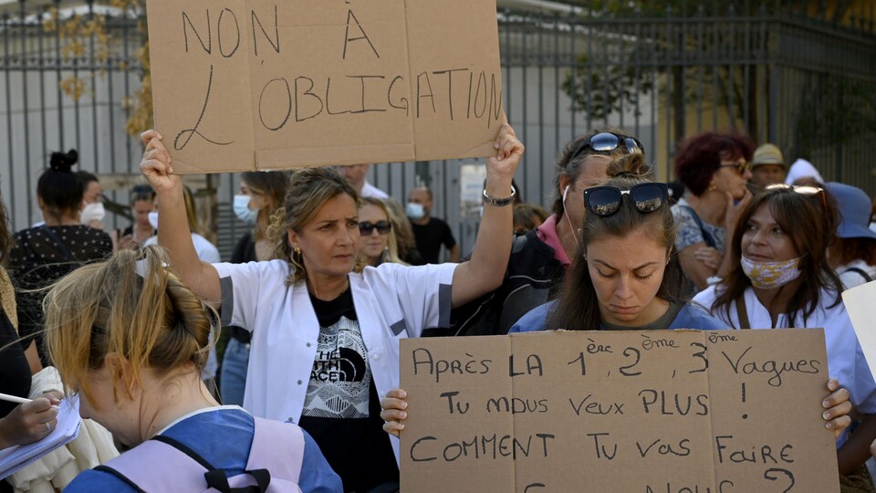 Des manifestants tiennent une affiche sur laquelle il est écrit : non à l'obligation vaccinale.