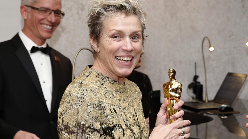L'actrice tient dans ses mains son trophée et sourit.