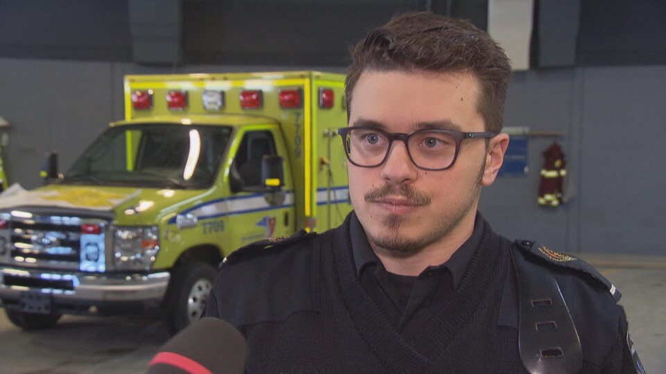 Un jeune ambulancier en entrevue devant une ambulance