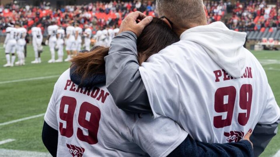 Un homme et une femme se recueillent sur un terrain de football.