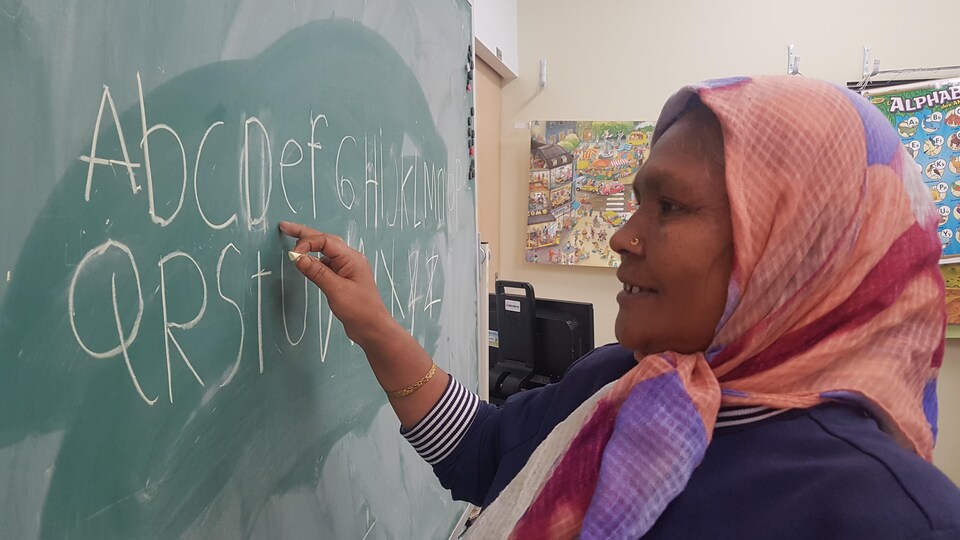 Une femme immigrante en train d'écrire au tableau d'une classe