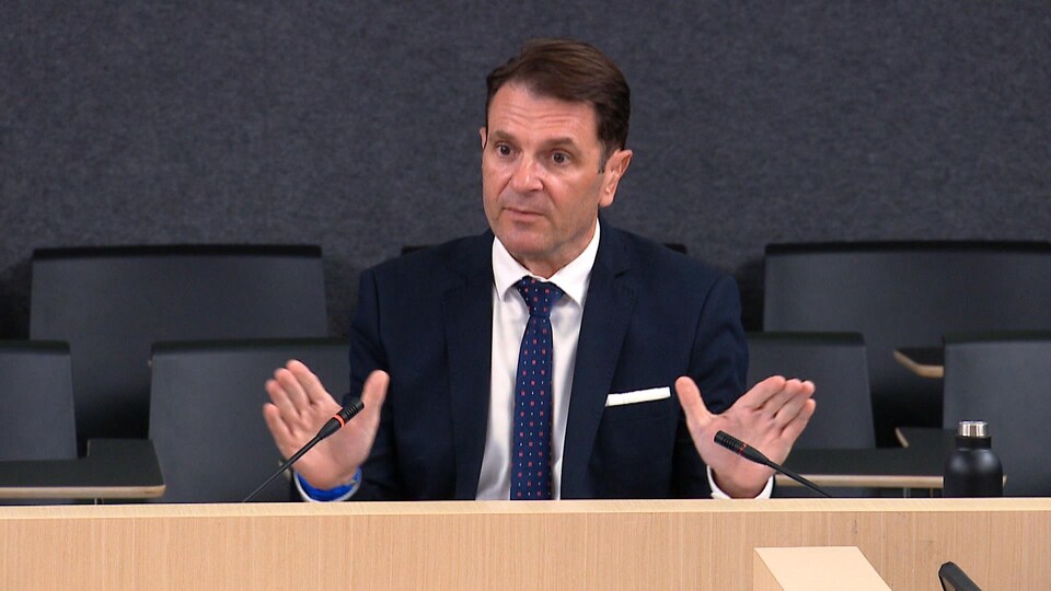 François Bonnardel installé dans une salle, répond à des interlocuteurs qui ne sont pas dans le cadre de la photo.