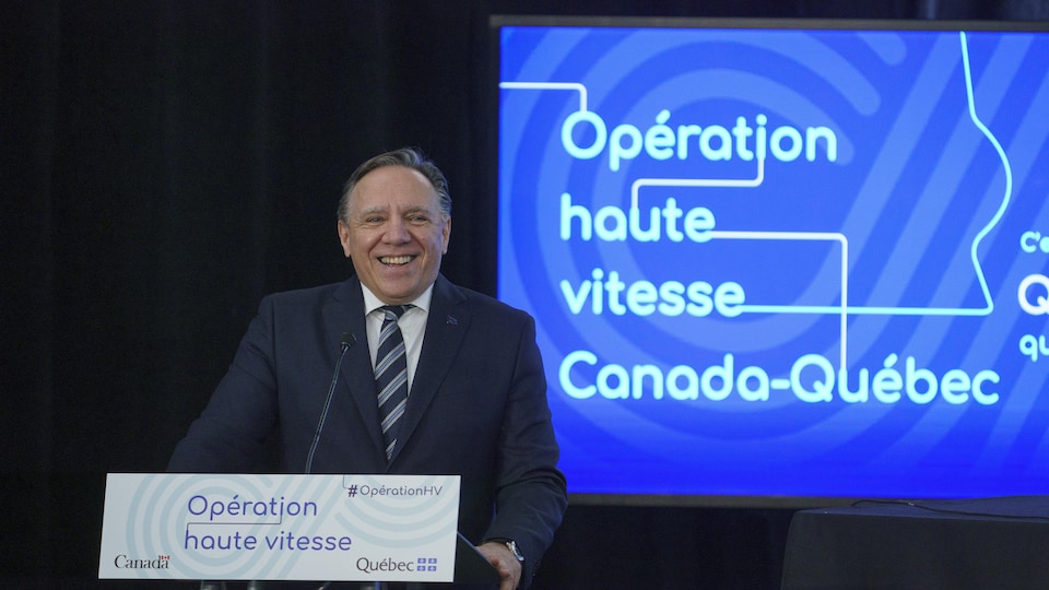Le premier ministre du Québec, souriant devant le micro.
