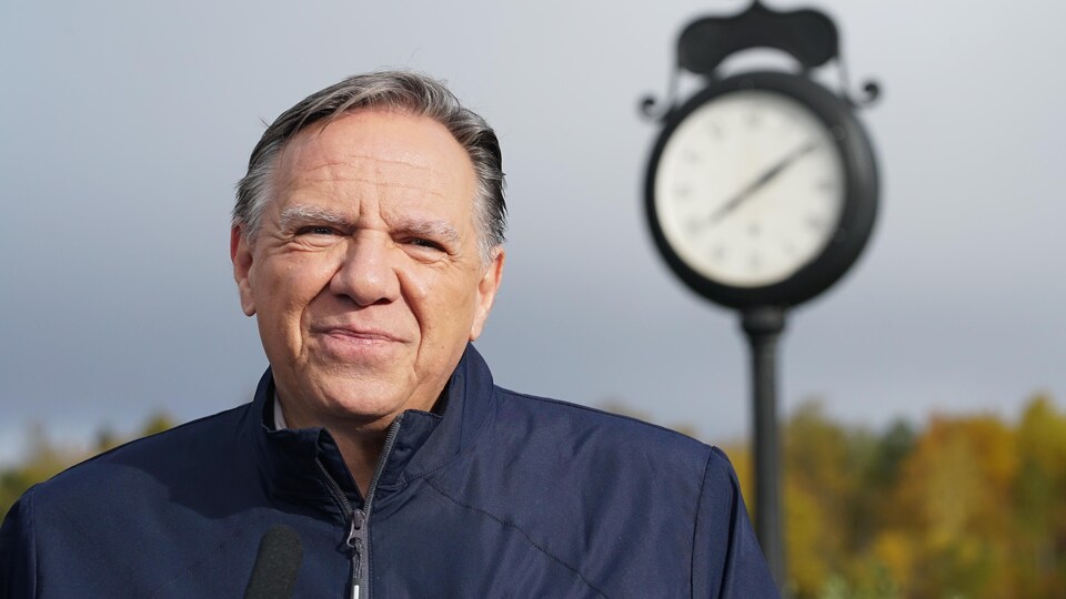 François Legault devant une horloge.