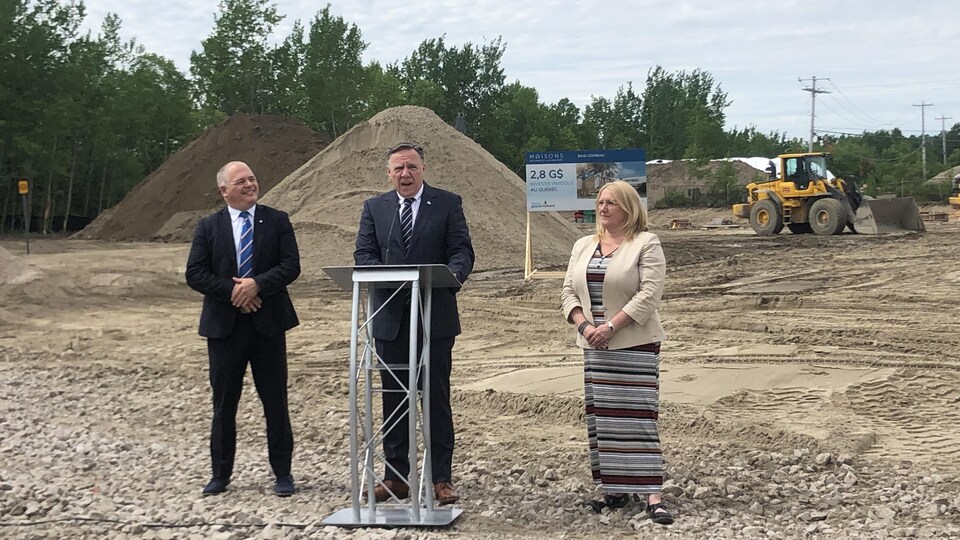 François Legault à un lutrin sur un chantier de construction, entouré de Jonatan Julien et de Manon Asselin. 
