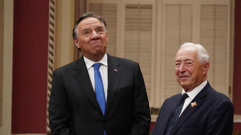 François Legault lève les yeux en esquissant un sourire, en compagnie de Michel Doyon, qui sourit aussi.