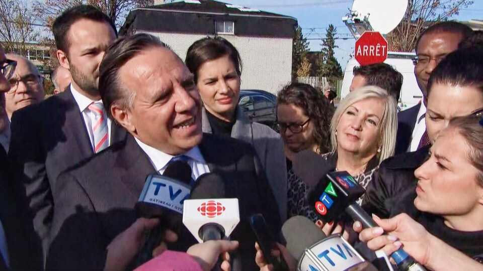 Le premier ministre parle aux médias à Gatineau, accompagné d'autres politiciens.