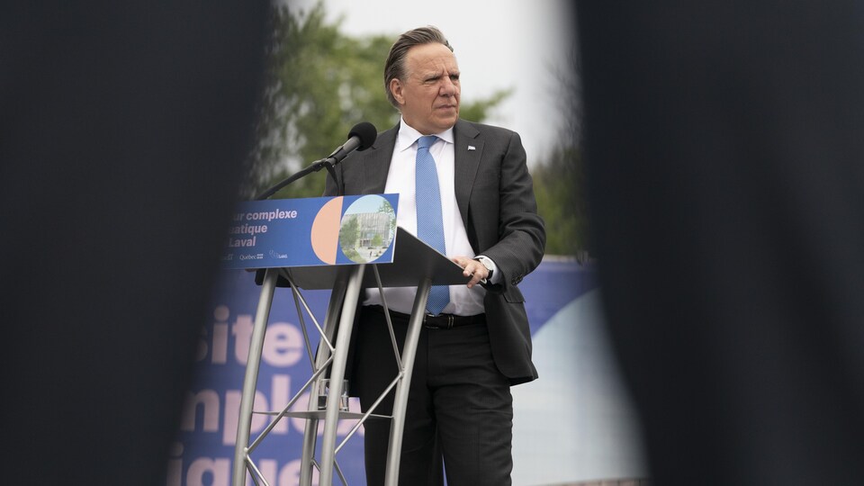 Le premier ministre Legault, debout à un lutrin lors d'une conférence de presse tenue à l'extérieur.