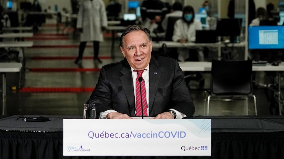 François Legault assis à une table durant un point de presse.                           